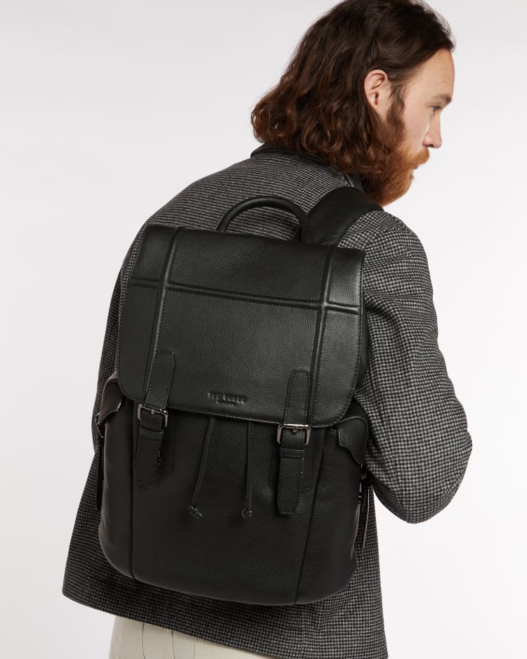 A bearded man wearing a men's leather backpack for work