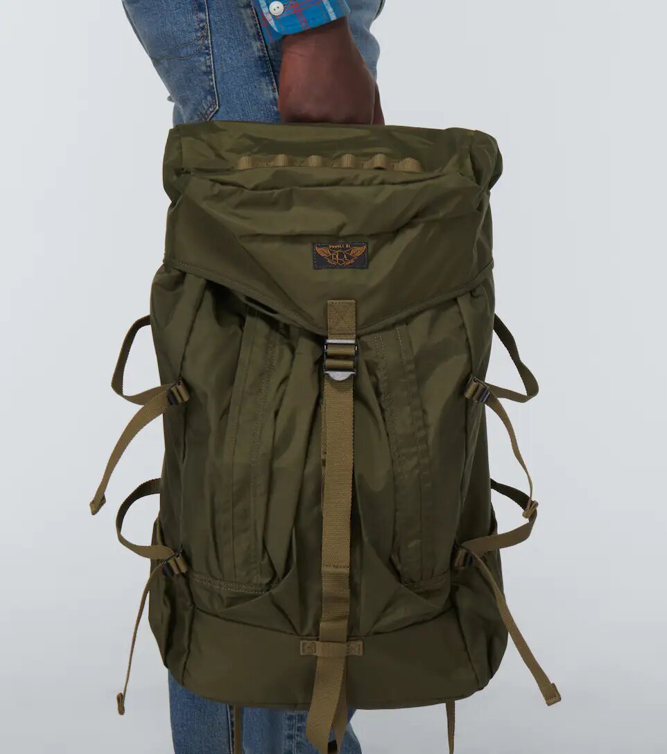 Man holding a khaki green hiking backpack