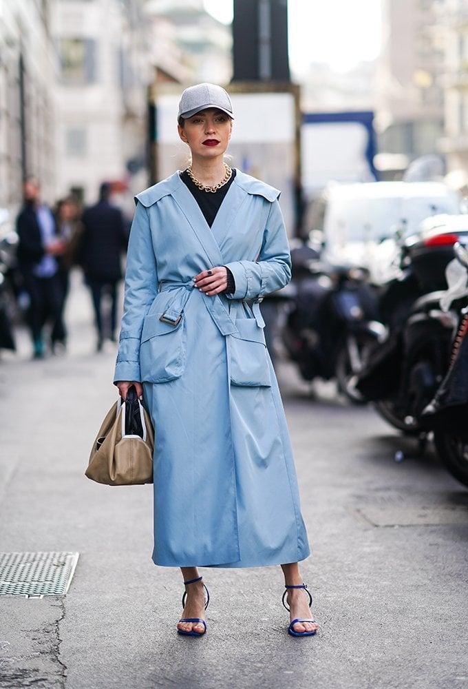 Woman wearing a fitted cap with a long blue trench coat