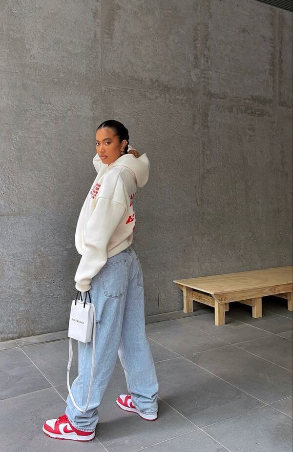 Woman wearing a white sweatshirt and boyfriend jeans with sneakers