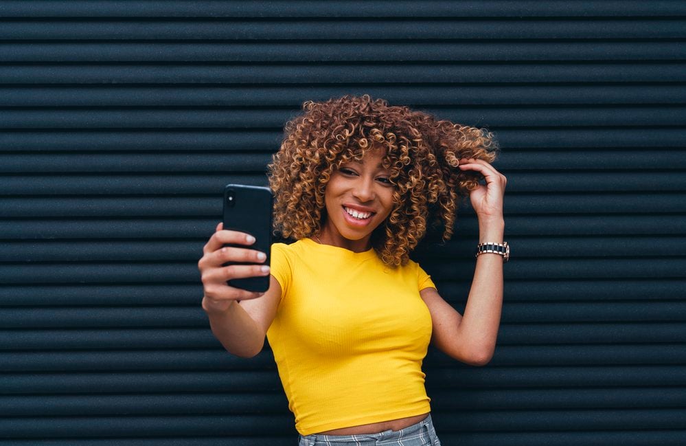 Woman wearing a yellow top taking a selfie