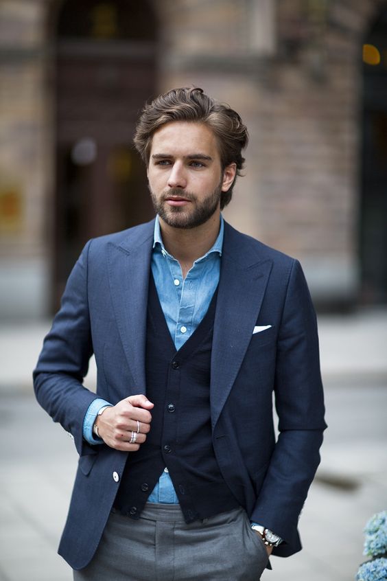 An elegant man wearing a shirt, cardigan, and jacket