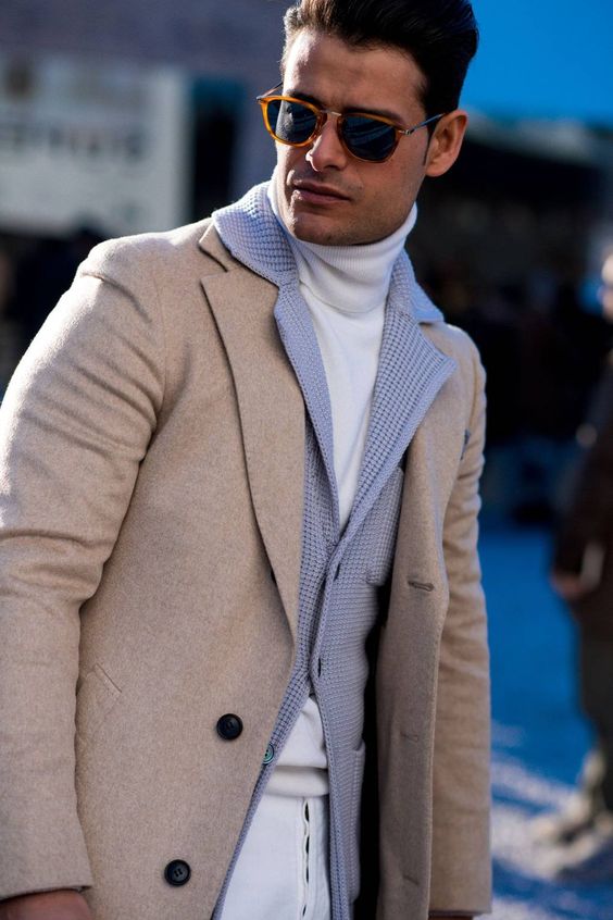 A man wearing a chunky knit cardigan and a jacket